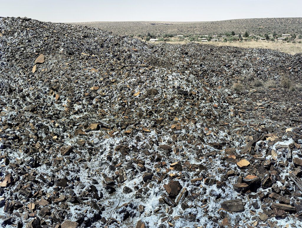 David Goldblatt b. 1930, d. 2018, South Africa Highly carcinogenic blue asbestos waste on the Owendale Asbestos Mine tailings dump, near Postmasburg, Northern Cape. The prevailing wind was in the direction of the mine official’s houses at right. 21 December 2002 (4_8739), 2002 Digital C-print in pigment inks on cotton rag paper 44 × 53 inches