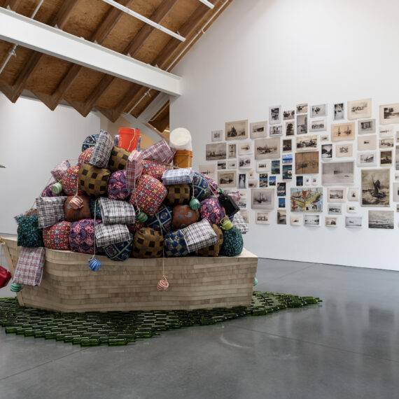 Barthélémy Toguo b. 1967, Cameroon Road to Exile, 2018 Wooden boat, cloth bundles, glass bottles, and plastic containers 120 × 60 × 45 inches