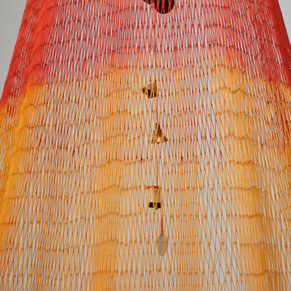 Carolina Caycedo (b. 1978, United Kingdom) Sol Sonora del Sur, 2022 Hand-dyed artisanal ﬁshing net, lead weights, gold-plated polished steel plate, copper bells, jade stone, and brass keys